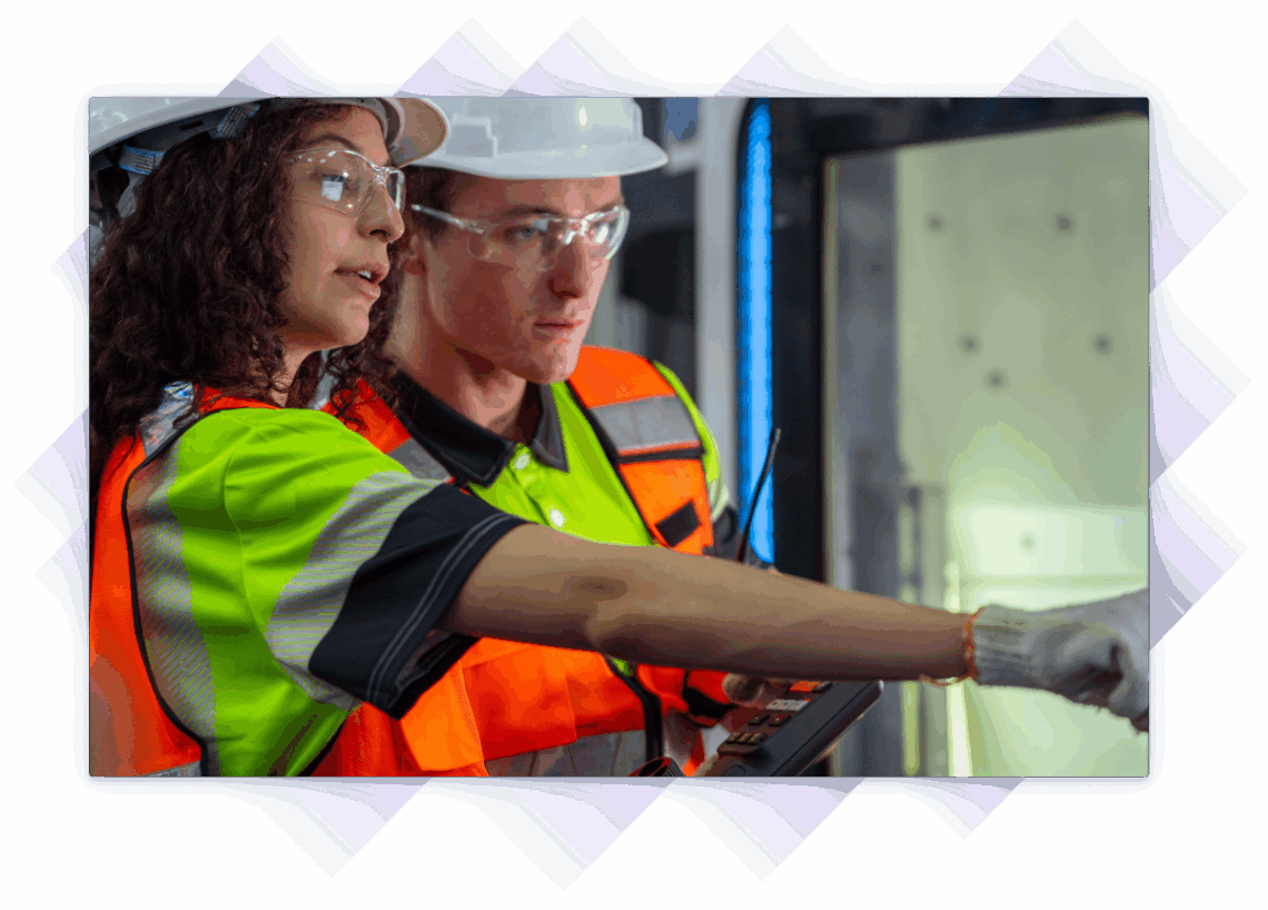 Two engineers in safety gear reviewing equipment controls and inspecting machinery.