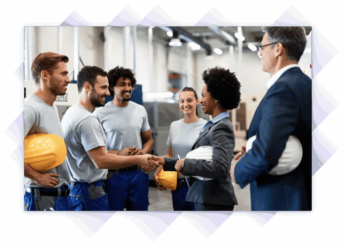 Female executive shaking hands with a factory worker in a group meeting with industrial staff.