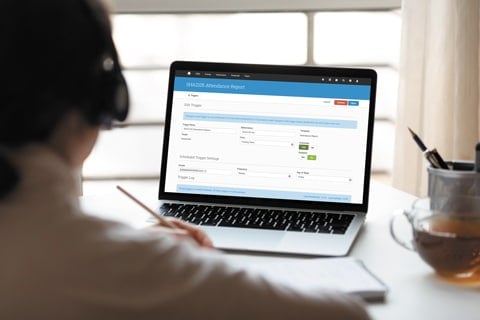 Woman at desk taking notes in front of a laptop with Administrate software on the screen.