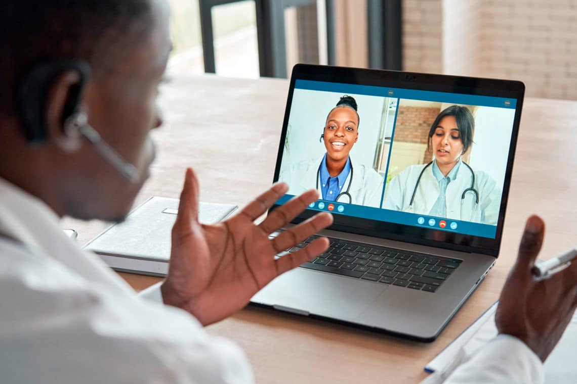 Male doctor gesturing on a video call with two woman doctors.