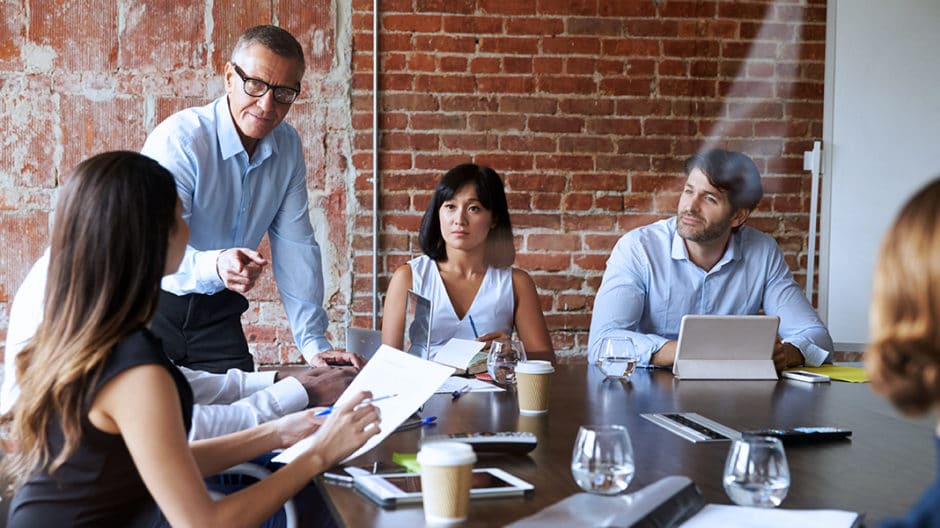 Businesspeople in a meeting in modern boardroom through a glass pane.