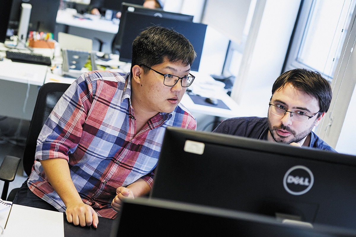 Two software engineers looking intently at a monitor.