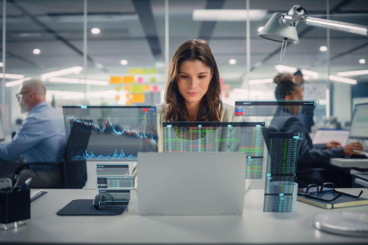 Woman sitting at office desk with data projected in front of her.