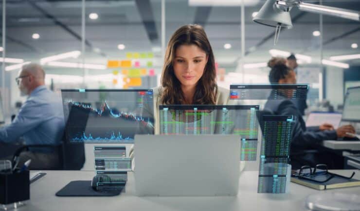 Woman sitting at office desk with data projected in front of her.