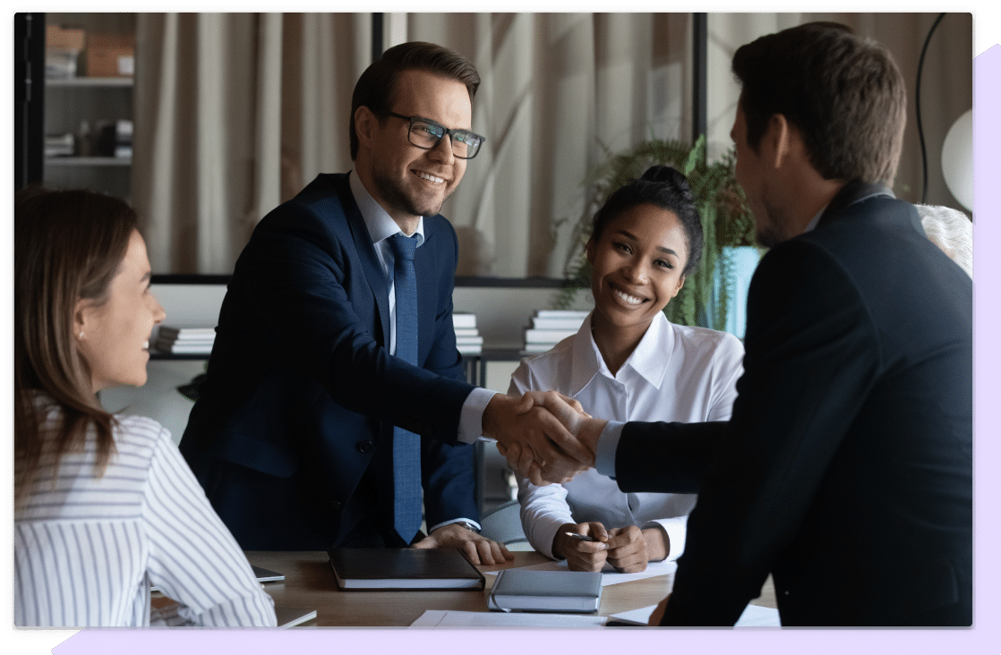 Four business people shake hands and smile having just formed a partnership.