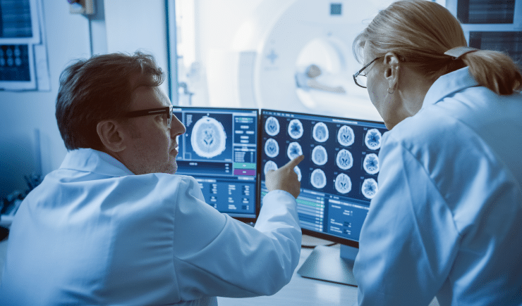 Medical professionals consult the results of an MRI scan, one professional points to an image from the results.