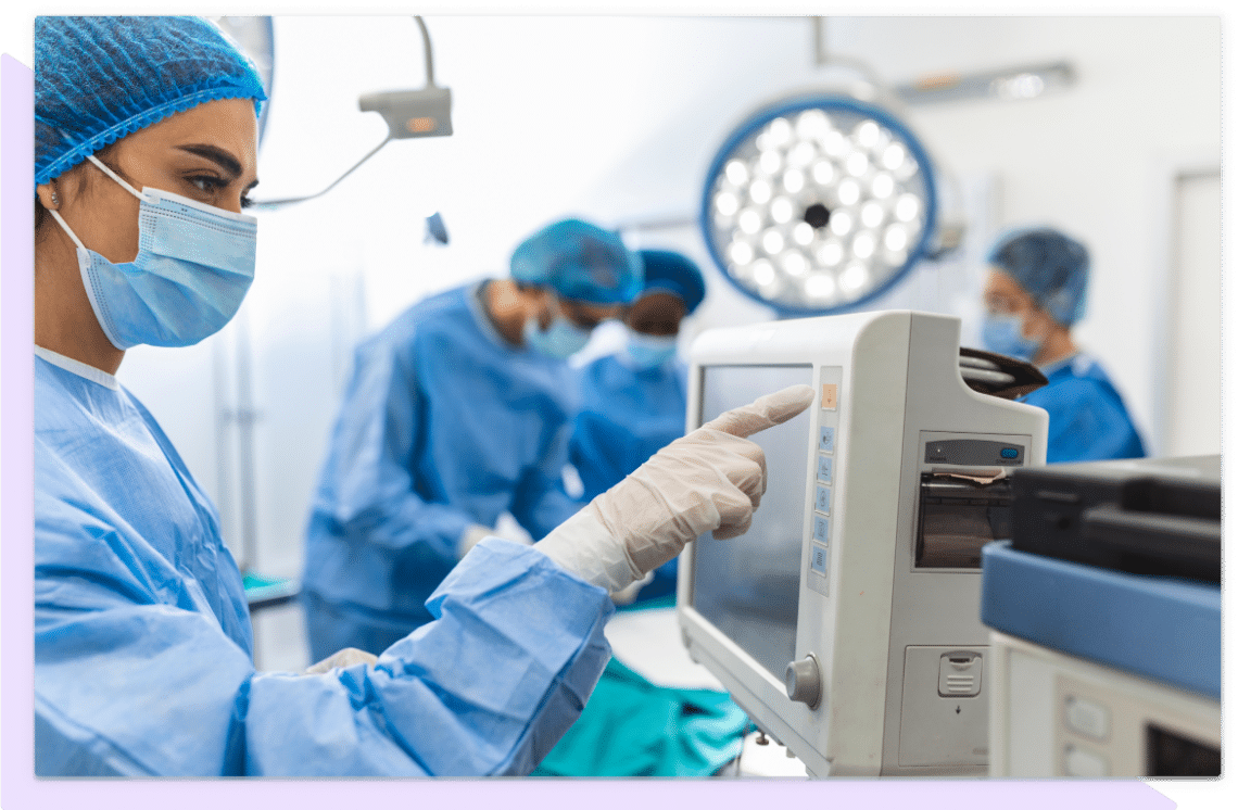 Medical professional in hospital uses machine while her colleagues work in the background.