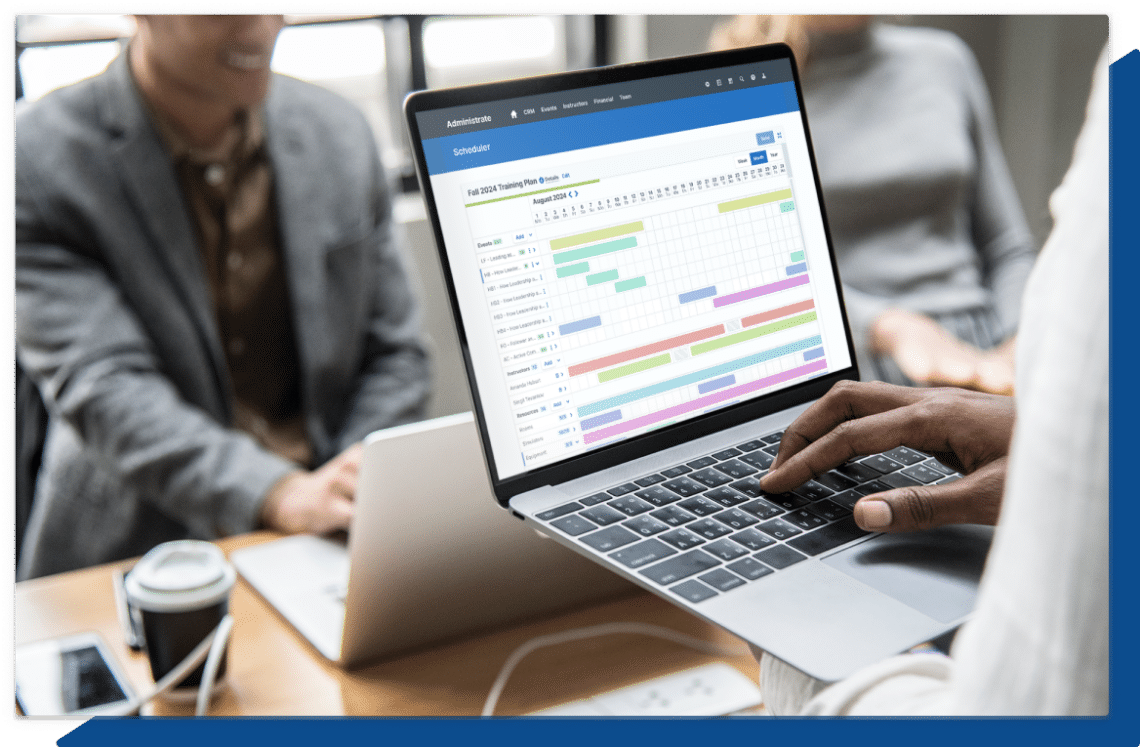 A screenshot of Administrate’s Scheduler on a laptop being held by a training manager, the tool is using AI-powered software to solve a complex training plan.