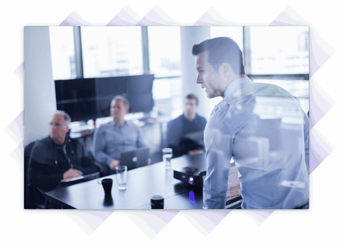 Business team in a boardroom meeting, attentively listening to a presenter with data projected on a screen.