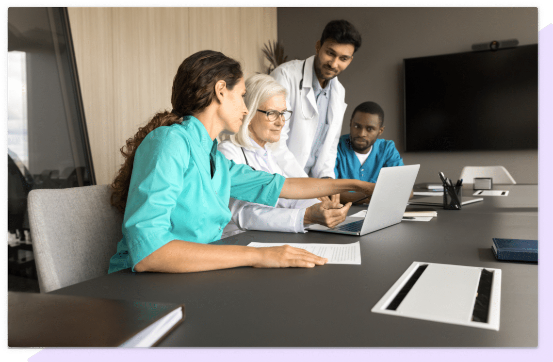 Four training professionals work together around a laptop to solve a training plan.
