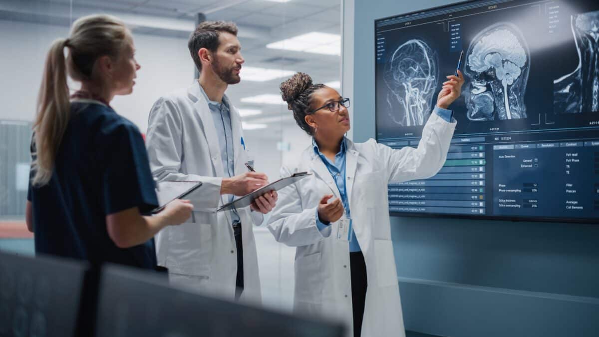 Doctors in lab coats engage in ILT training, pointing to an X ray while learning about an illness.