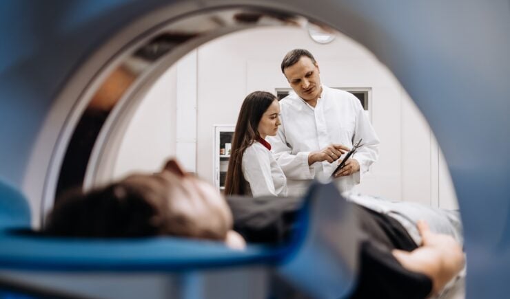 A doctor completes an MRI examination while engaging with a younger doctor.