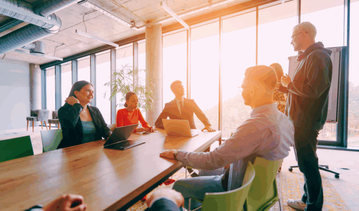 Training teams discusses automated communications in an open boardroom.