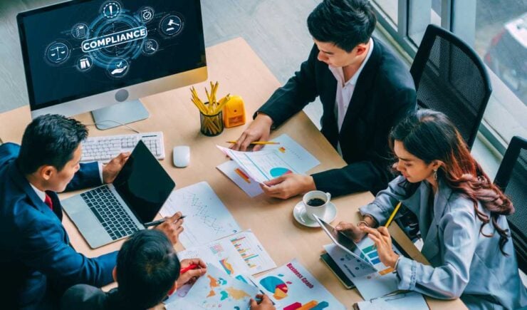 Training professionals at a desk working together to solve compliance issues.